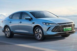 A light blue BYD Qin PLUS DM-i sedan parked by a scenic waterfront.