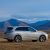A silver SUV parked on a grassland with mountains in the background.