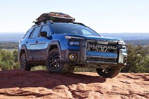 Mud-streaked blue off-road Mud-streaked blue off-road SUV parked on a red rock overlook, with gear loaded on its roof rack and expansive desert views behind. parked on a red rock overlook, with gear loaded on its roof rack and expansive desert views behind.