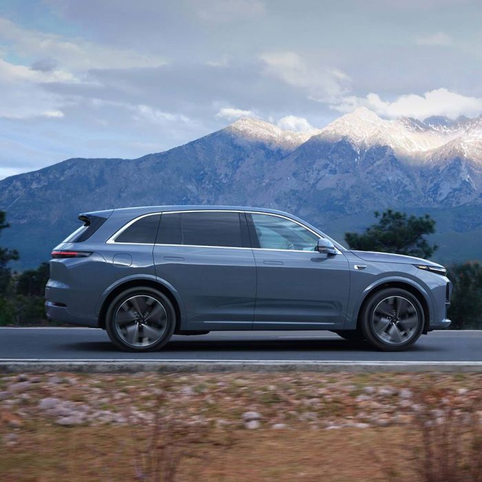 A gray SUV driving on a road with mountains in the background.