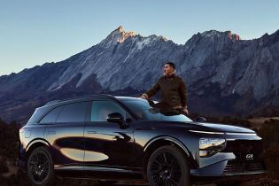 A man standing next to a black Xpeng G9 SUV, with a majestic mountain range in the background.