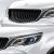 Close - up of a white car's grille and headlight.