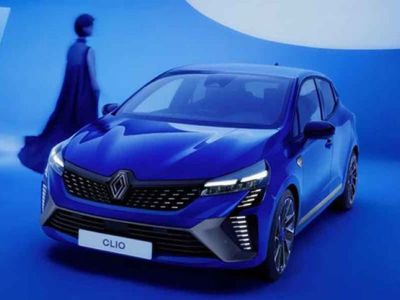 A blue Renault Clio in a blue - themed studio setting, with a person in a long dress in the background.