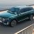 A dark green Geely SUV by the water.