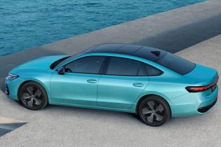 A teal sedan parked by the sea.