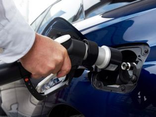 EV fast charging: Hand inserting a DC fast charger into a blue electric vehicle's port, showcasing modern sustainable mobility.