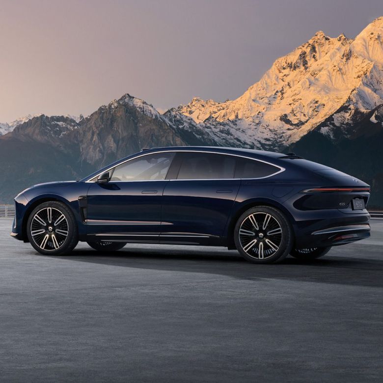 Side view of a dark blue NIO ET9 electric car with snow-capped mountains in the background.