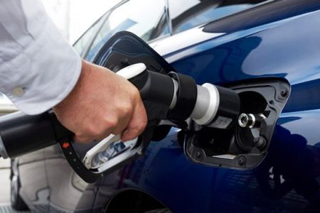 EV fast charging: Hand inserting a DC fast charger into a blue electric vehicle's port, showcasing modern sustainable mobility.