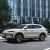 A beige BYD Song PLUS DM-i SUV on an urban road, with a modern glass building and trees in the background, showcasing its sleek design and urban appeal.