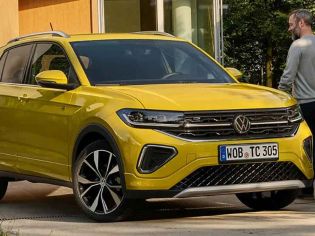 Bright yellow Volkswagen SUV (with VW logo, alloy wheels) parked by a building; a man walks beside it.