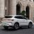 Rear-side view of a white BYD Song Plus DM-i SUV, showcasing its sleek design, full-width taillights, and stylish wheels, parked on a road in front of a grand stone building.