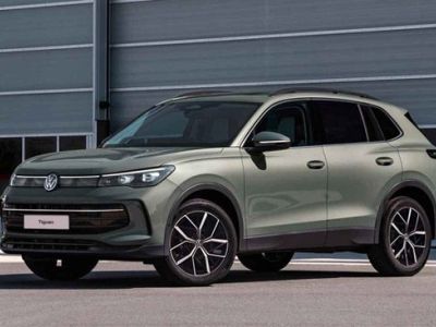 A light green Volkswagen Tiguan SUV parked in front of a modern industrial building.