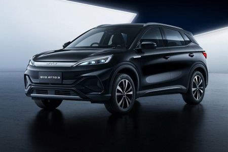 Sleek black BYD ATTO 3 electric SUV showcased in a modern, minimalist studio setting with a reflective dark floor.