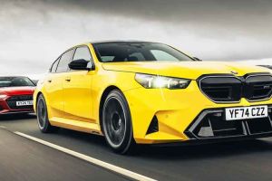 A yellow BMW (license plate YF74 CZZ) and a red Audi (license plate KY24 TEU) driving on a road.