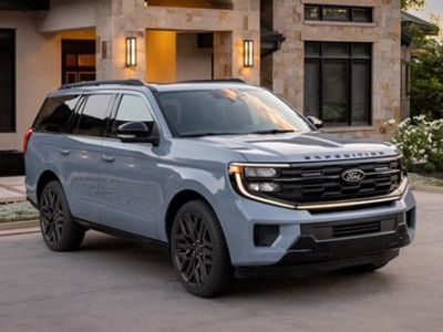 Light blue 2026 Ford Expedition with black accents parked on a driveway in front of a modern stone and stucco home.