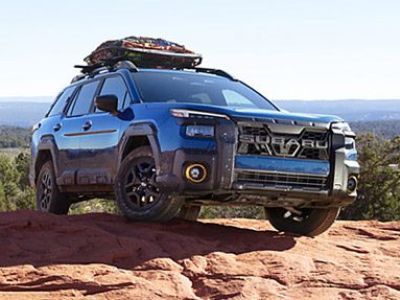 Mud-streaked blue off-road Mud-streaked blue off-road SUV parked on a red rock overlook, with gear loaded on its roof rack and expansive desert views behind. parked on a red rock overlook, with gear loaded on its roof rack and expansive desert views behind.