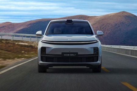 The 2024 Leapmotor C11 drives on a scenic road, with rolling hills in the background, showcasing its sleek electric SUV design and advanced autonomous driving sensor setup.