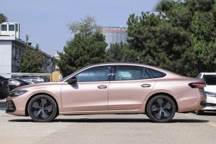 Side view of a pink sedan parked in an outdoor area, with trees and buildings in the background.