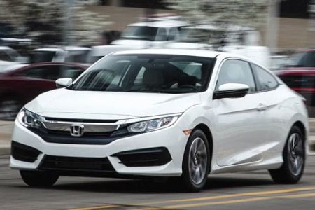 White Honda Civic Coupe: Sleek two-door coupe in motion on a city street, showcasing modern design and dynamic performance.