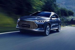 Dark SUV (BYD Song Plus) driving on a curvy road, surrounded by green mountains (motion blur effect).