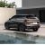 Rear view of Geely BinYue L SUV by a building and water.