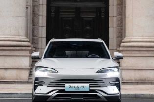Front view of BYD Song Plus DM-i 2025 model, a silver SUV with distinctive Ocean X Face grille and sleek headlights, parked in front of a grand stone building.