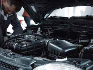 Close-up view of car engine bay with hood open, auto mechanic inspecting vehicle mechanical parts inside repair service workshop