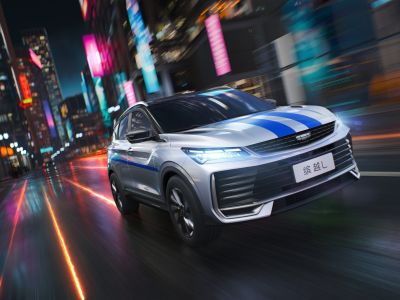 A Geely BinYue L SUV with blue stripes driving through a vibrant, neon - lit city at night.