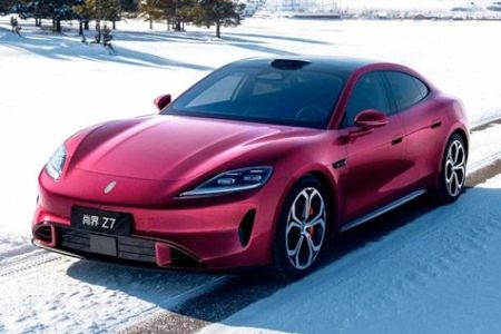 Sleek red all-electric sports sedan, the Xiaomi SU7, displayed on a snowy road, showcasing futuristic design and alloy wheels.