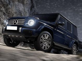 The Mercedes-Benz G-Class SUV, in a deep blue finish, navigates rocky terrain under a starry night sky, showcasing its iconic off-road capability, bold design, and luxury engineering.