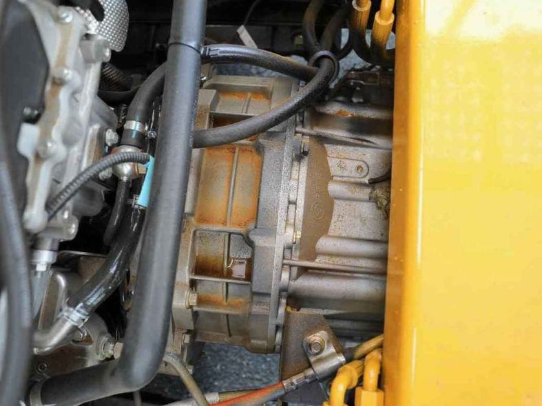 Close - up of a rusty mechanical component with hoses, likely in an engine bay.