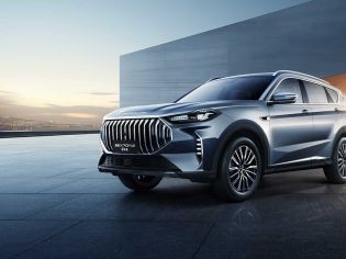 A silver Jetour X70 PLUS SUV parked on a modern, sleek pavement with a minimalist architectural background and a scenic sunset view.
