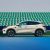 A light - colored BYD Yuan Plus electric SUV parked on a tennis court with green seats in the background.