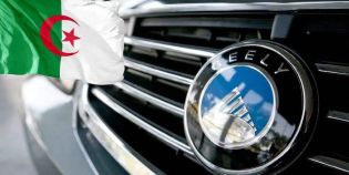Close-up of a Geely car emblem on a grille, paired with the Algerian flag in the background, linking the automaker to Algeria.