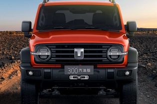 Front view of an orange off - road SUV parked on a rocky desert terrain.