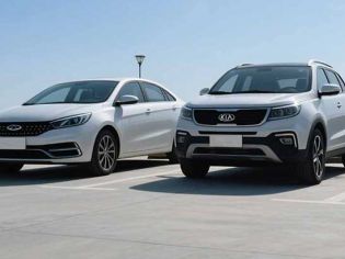 Two white cars, a sedan and an SUV, parked in an open area under a clear blue sky.