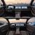 Interior of a Geely car with dual - screen display, showcasing two views against a mountainous landscape at sunrise/sunset.