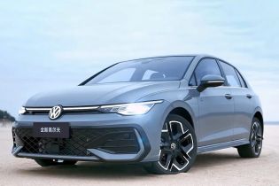 A gray Volkswagen Golf parked on a sandy area under a clear sky.