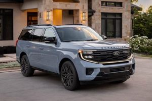 Light blue 2026 Ford Expedition with black accents parked on a driveway in front of a modern stone and stucco home.