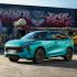 A turquoise Fengon T5 EVO SUV parked in front of a vibrant graffiti-covered container, showcasing a trendy urban scene with colorful street art.