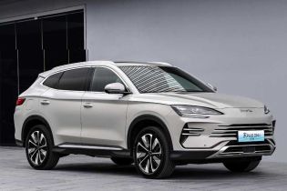 A silver BYD Song PLUS DM-i SUV parked in front of a modern building, highlighting its sleek design and stylish alloy wheels in an urban setting.