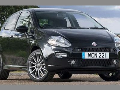 A black Fiat hatchback with license plate "WCN 221", parked on a gravel area with a rural landscape of trees and buildings in the background, showcasing its sleek design.