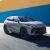 A sleek silver SUV driving on a road, set against a vibrant blue and yellow wall, highlighting its modern design and dynamic appearance.