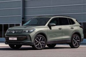 A light green Volkswagen Tiguan SUV parked in front of a modern industrial building.