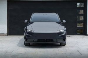 Front view of a sleek black electric SUV parked in a driveway, connected to a home charging station, with a modern garage and landscaped area, embodying eco-friendly and minimalist design.
