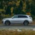 A silver SUV driving on a road with a forest in the background.