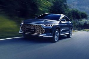 Dark SUV (BYD Song Plus) driving on a curvy road, surrounded by green mountains (motion blur effect).