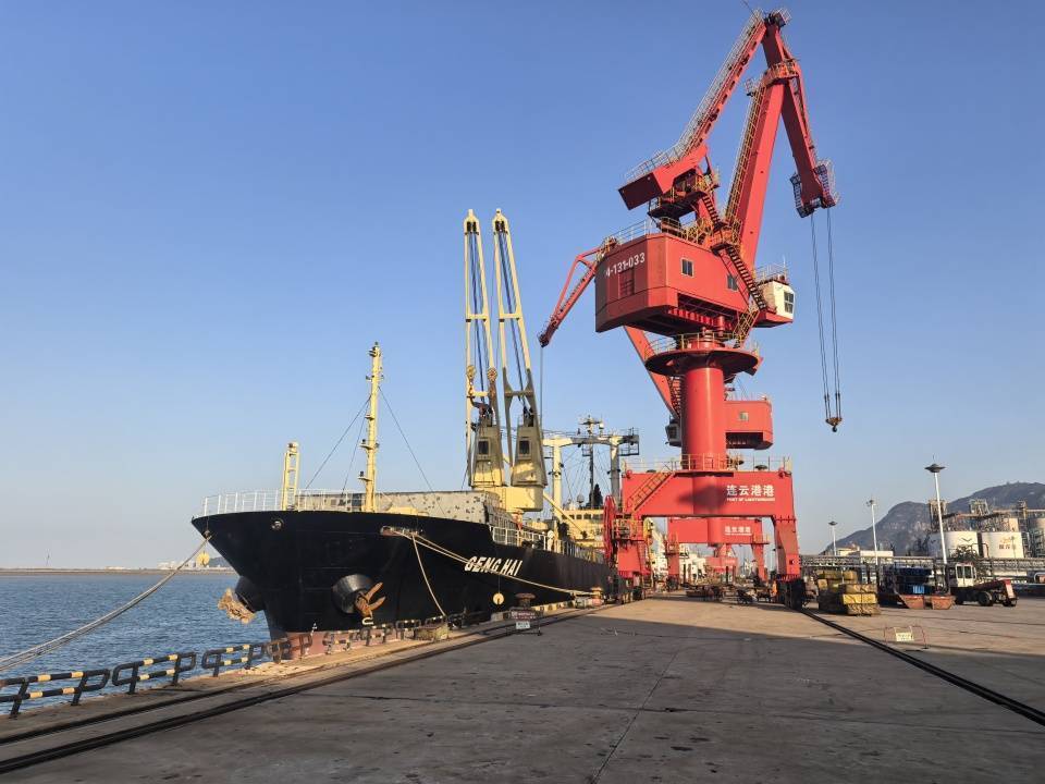A large ship docked at Lianyungang Port, with a prominent red crane and clear blue sky in the background.