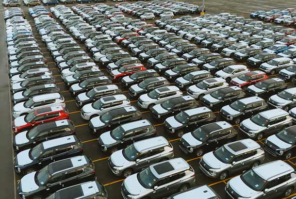 Aerial view of a large parking lot filled with neatly arranged cars of various colors.