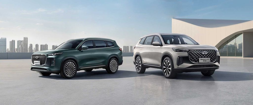 Two Chery Tiggo 8 PLUS SUVs, one dark green and one silver, parked on a smooth surface with a cityscape in the background.